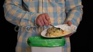 男人用盘子刮<strong>一个鸡腿</strong>，米饭，青豆放进垃圾桶